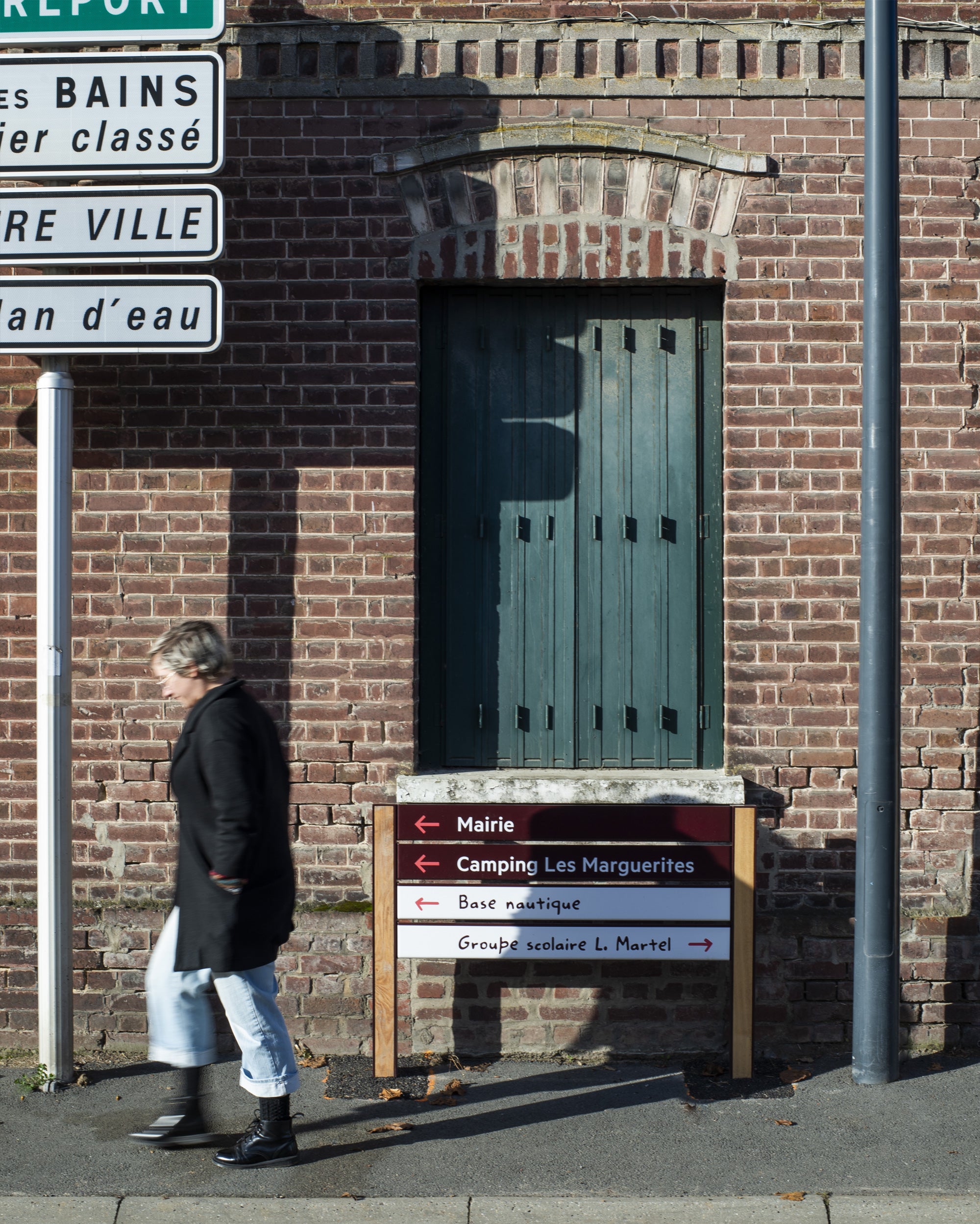 femme marchant devant signalétique communale