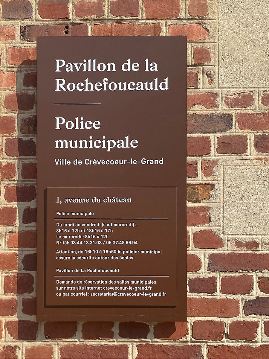Détail d'enseigne murale sur-mesure avec adresse, horaires et contact