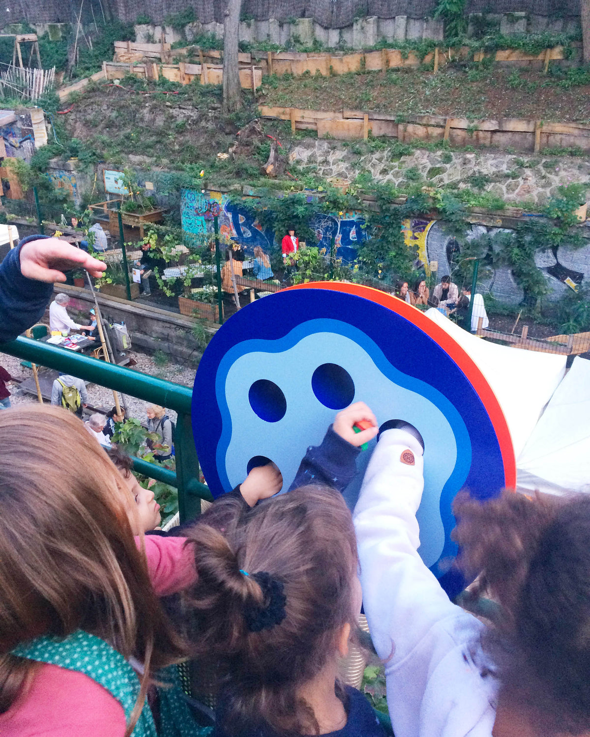 Enfants déposant des bouchons par les orifices de l'installation ludique