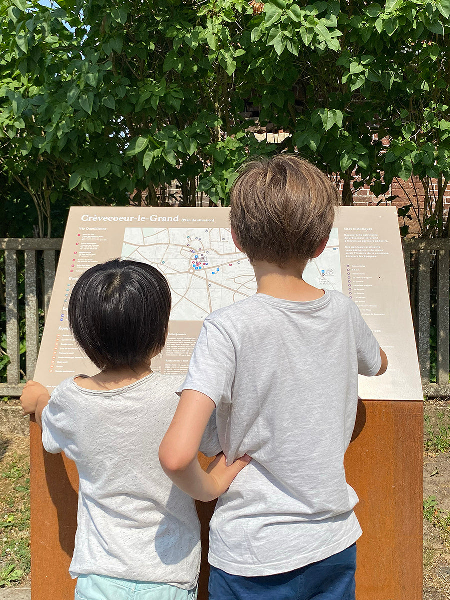 Enfants consultent un relais info service incliné ave un socle en corten
