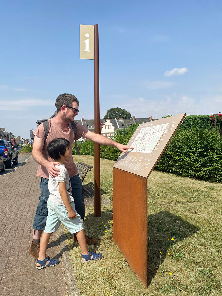 Père montrant une information à son fils sur un relais incliné à hauteur d'enfant