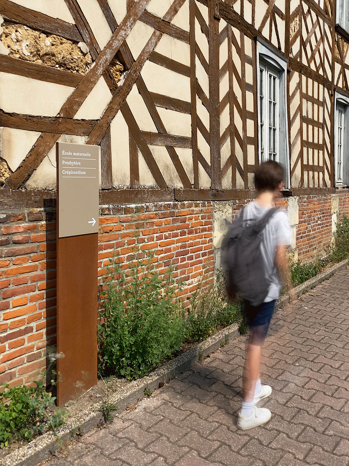 Enfant guidé par une signalétique piétonne directionnelle en zone patrimoniale