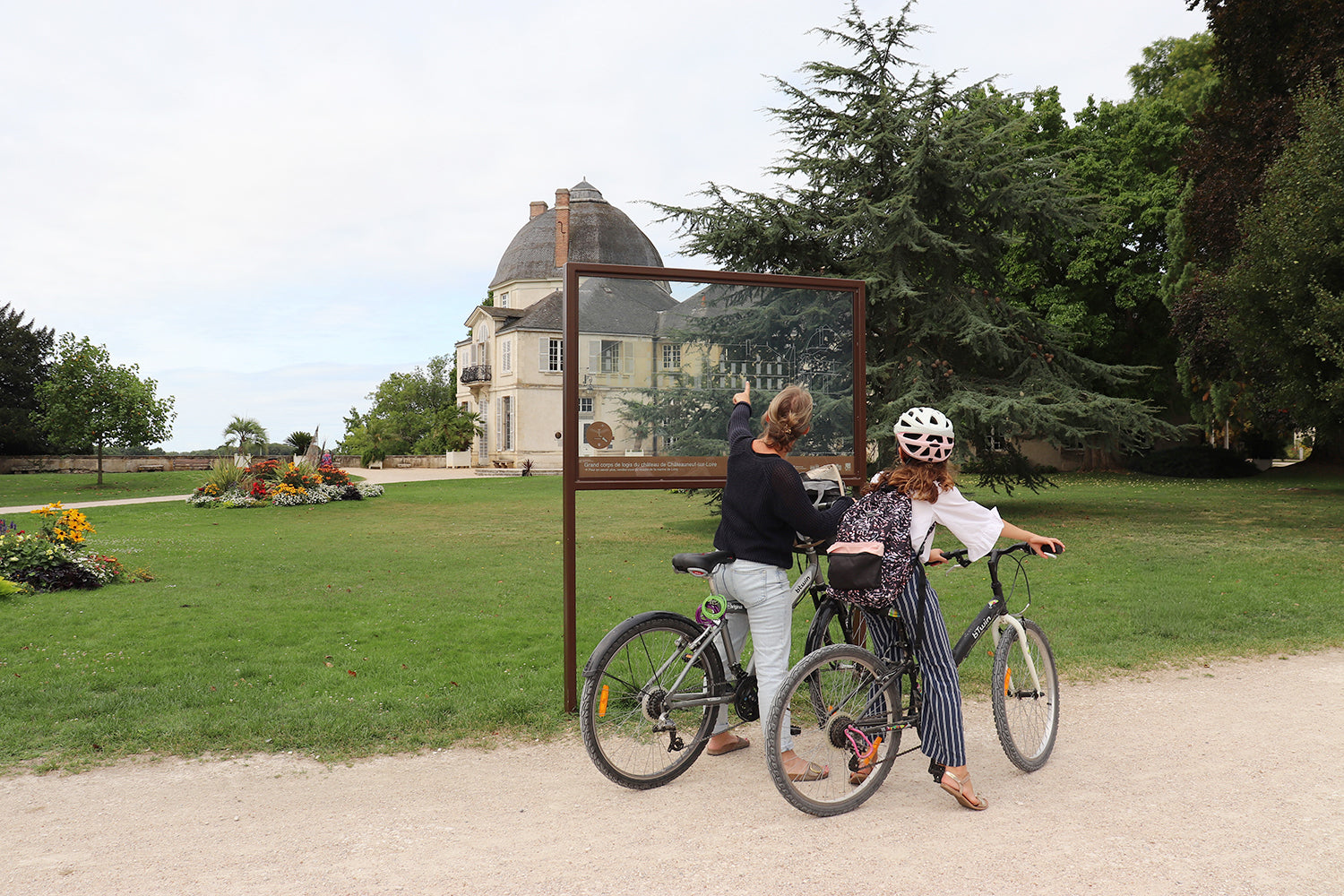 Visiteurs à vélo découvrent l’histoire patrimoniale via un support médiatique transparent sur les allées d’un parc public